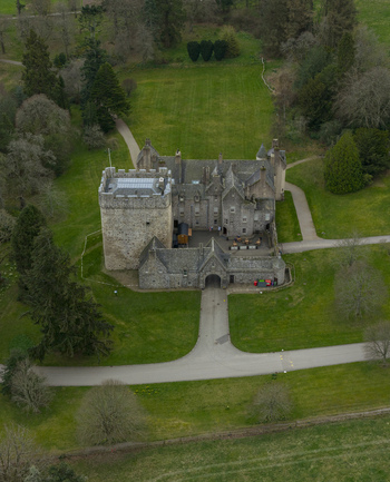 Aerial view of Drum Castle featuring its historic stone tower and courtyard surrounded by lush green lawns and woodland Drumoak Scotland United Kingdom.