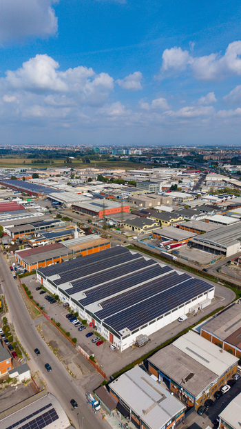 Aerial view of manufacturing and logistics buildings with solar panels on rooftops in an industrial area in San Giuliano Milanese Lombardy Italy.