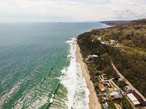 Aerial view of Fichoza Beach Veteran featuring the Black Sea coastline with crashing waves dense forest and coastal villas in Varna Varna Bulgaria. Aerial view of Fichoza Beach Veteran featuring the Black Sea coastline with crashing waves dense forest and coastal villas in Varna Varna Bulgaria.