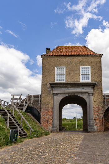 View of the historic Wijkse Poort city gate with brick masonry an arched stone entrance and wooden stairs leading to the ramparts in Heusden North Brabant Netherlands.
