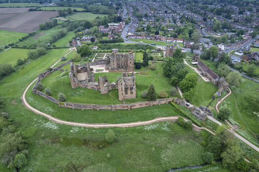 Aerial view of the historic ruins of Kenilworth Castle and its Elizabethan Garden surrounded by green lawns and trees with the town of Kenilworth in Kenilworth England United Kingdom.