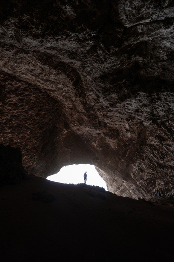 View of the massive entrance of Hoq Cave with a silhouette of a person standing against the bright daylight in Socotra Socotra Yemen. View of the massive entrance of Hoq Cave with a silhouette of a person standing against the bright daylight in Socotra Socotra Yemen.