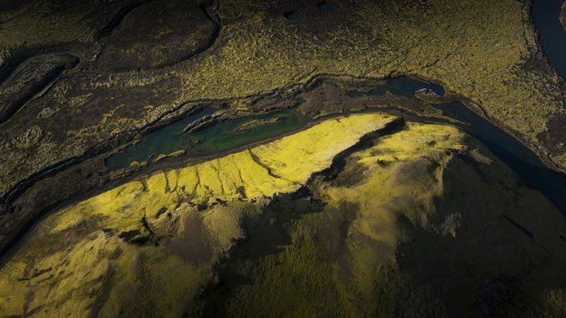 Aerial view of vibrant green moss covered volcanic terrain surrounding the deep blue waters of Langisjor lake under dramatic lighting in Vik Myrdalshreppur Iceland. Aerial view of vibrant green moss covered volcanic terrain surrounding the deep blue waters of Langisjor lake under dramatic lighting in Vik Myrdalshreppur Iceland.