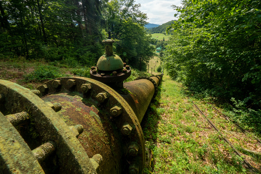 View of the historic penstock and valve of the Jasenie Hydroelectric Power Plant running through a lush forest in Jasenie Banska Bystrica Regio Slovakia.
