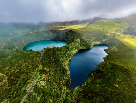 Aerial view of the stunning contrast between the turquoise and deep blue lakes nestled within the verdant crater of Lake Comprida Flores Azores Portugal.