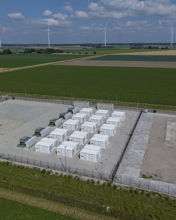 Aerial view of the Battery Energy Storage System at Wind Park with rows of white storage containers on a concrete pad amidst green fields in Dronten Flevoland Netherlands. Aerial view of the Battery Energy Storage System at Wind Park with rows of white storage containers on a concrete pad amidst green fields in Dronten Flevoland Netherlands.