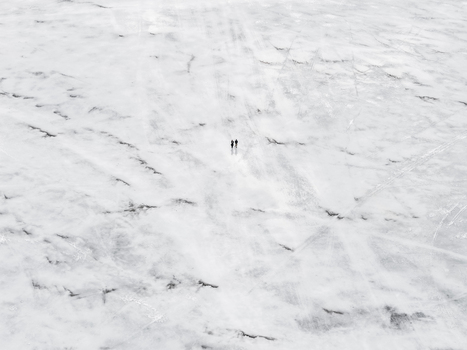 Aerial view of two people walking across the vast frozen snow covered surface of Lake Galve near Trakai Castle in Trakai Vilnius County Lithuania. Aerial view of two people walking across the vast frozen snow covered surface of Lake Galve near Trakai Castle in Trakai Vilnius County Lithuania.