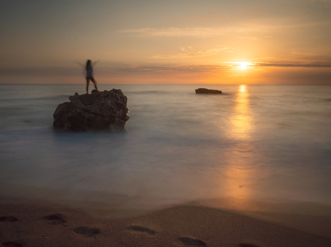 View of a lone figure triumphantly silhouetted against the radiant sunset atop a rocky outcrop amidst the tranquil silky waters Kathisma Lefkada Greece. View of a lone figure triumphantly silhouetted against the radiant sunset atop a rocky outcrop amidst the tranquil silky waters Kathisma Lefkada Greece.
