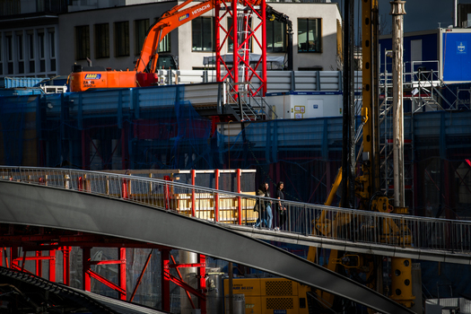 Zurich Switzerland 02 April 2023 View of a construction site a pedestrian bridge and people walking juxtaposing the stark industrial elements with the everyday life of the city. Zurich Switzerland 02 April 2023 View of a construction site a pedestrian bridge and people walking juxtaposing the stark industrial elements with the everyday life of the city.