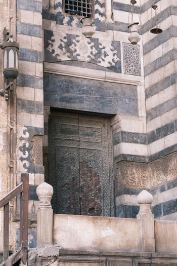 View of the ornate entrance of Al Ghuri Dome with striped masonry and intricate carvings in Cairo Egypt. View of the ornate entrance of Al Ghuri Dome with striped masonry and intricate carvings in Cairo Egypt.