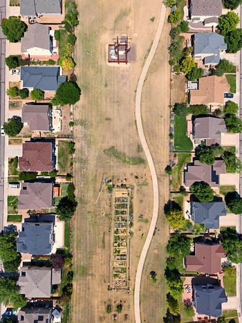 Aerial view of a suburban park featuring a winding walking path a community garden and residential houses in Thornton Colorado United States. Aerial view of a suburban park featuring a winding walking path a community garden and residential houses in Thornton Colorado United States.