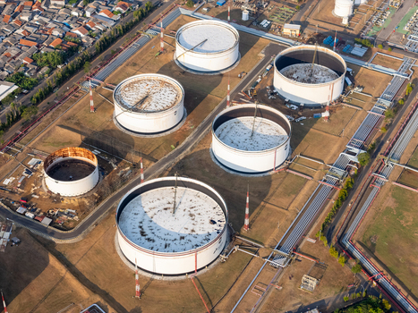Aerial view of large industrial oil storage tanks and complex pipeline infrastructure at a refinery facility in Cilacap Central Java Indonesia. Aerial view of large industrial oil storage tanks and complex pipeline infrastructure at a refinery facility in Cilacap Central Java Indonesia.
