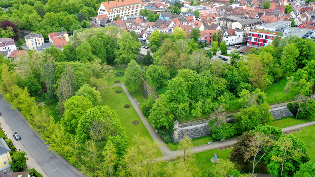 Aerial view of Stadtpark featuring lush green trees historic stone walls and surrounding residential buildings in Forchheim Bayern Germany. Aerial view of Stadtpark featuring lush green trees historic stone walls and surrounding residential buildings in Forchheim Bayern Germany.