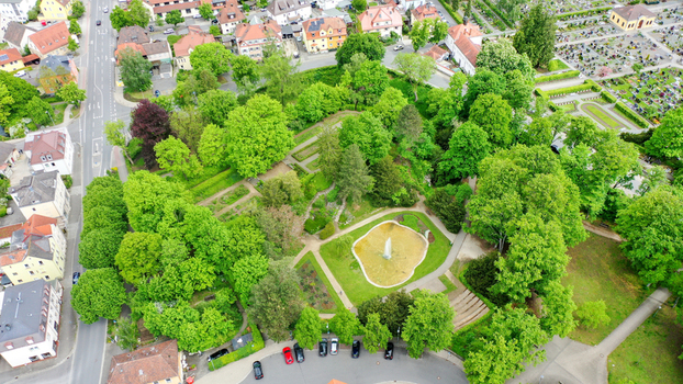 Aerial view of Stadtpark featuring lush green trees a central fountain pond and surrounding residential houses in Forchheim Bayern Germany. Aerial view of Stadtpark featuring lush green trees a central fountain pond and surrounding residential houses in Forchheim Bayern Germany.