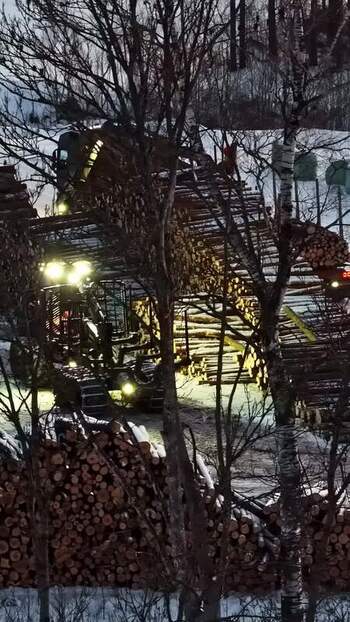 Aerial view of logging harvester in snowy forest Latvia.