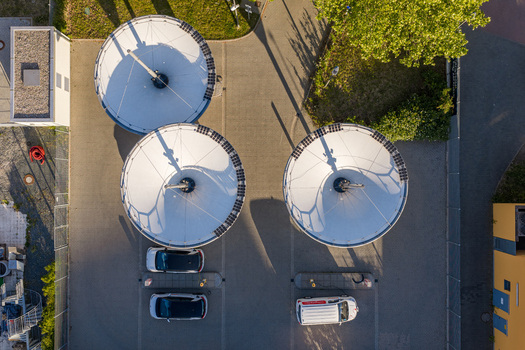 Aerial view of the ENTEGA Charging Station featuring large white solar umbrellas and electric vehicles parked on the paved lot in Darmstadt Hessen Germany. Aerial view of the ENTEGA Charging Station featuring large white solar umbrellas and electric vehicles parked on the paved lot in Darmstadt Hessen Germany.