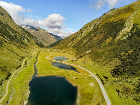 Aerial view of the Silvretta Hochalpenstrasse winding through the alpine valley with mountain lakes lush green meadows and steep slopes in Partenen Vorarlberg Austria. Aerial view of the Silvretta Hochalpenstrasse winding through the alpine valley with mountain lakes lush green meadows and steep slopes in Partenen Vorarlberg Austria.
