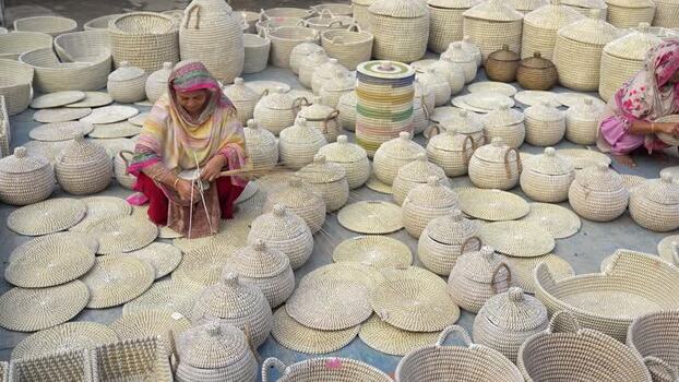 View of women weaving traditional baskets in Bangladesh. View of women weaving traditional baskets in Bangladesh.