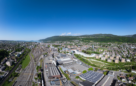 Aerial view of the industrial district and modern architecture of the Swatch and Omega campus with railway tracks and lush green hills in Biel Bienne Canton of Bern Switzerland.