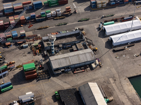 Aerial view of the industrial port area with stacked shipping containers warehouses a control tower and cargo storage in Bajos de Haina San Cristobal Provinc Dominican Republic.
