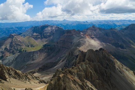 Aerial view of Mount Sneffels and the rugged peaks of the San Juan Mountains in the Rocky Mountains featuring dramatic rocky ridges and deep valleys in Ouray County Colorado United States. Aerial view of Mount Sneffels and the rugged peaks of the San Juan Mountains in the Rocky Mountains featuring dramatic rocky ridges and deep valleys in Ouray County Colorado United States.