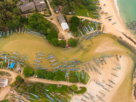 Aerial view of traditional outrigger fishing boats moored in a lagoon surrounded by lush palm trees and sandy shores in Dodanduwa Southern Province Sri Lanka. Aerial view of traditional outrigger fishing boats moored in a lagoon surrounded by lush palm trees and sandy shores in Dodanduwa Southern Province Sri Lanka.