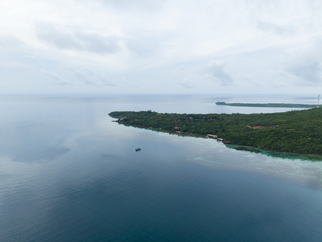 Aerial view of a boat sailing near a lush green island under a cloudy sky Karimunjawa Central Java Indonesia.