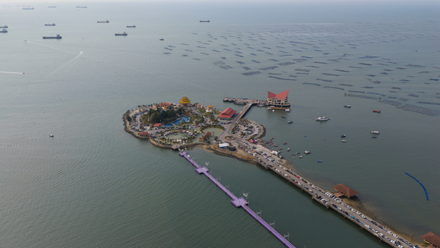 Aerial view of Koh Loi island featuring its temple bridge and parking area surrounded by the sea with boats and aquaculture nets in Si Racha Chon Buri Thailand. Aerial view of Koh Loi island featuring its temple bridge and parking area surrounded by the sea with boats and aquaculture nets in Si Racha Chon Buri Thailand.