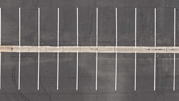Aerial view of an empty asphalt parking lot with white painted parking space lines and a concrete divider in Boulder Colorado United States. Aerial view of an empty asphalt parking lot with white painted parking space lines and a concrete divider in Boulder Colorado United States.