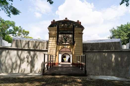 View of the historic entrance to the Star Fort featuring a stone archway with a coat of arms and a wooden bridge under a bright sky in Matara Southern Province Sri Lanka.