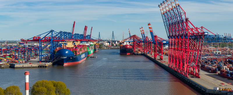 Aerial view of Waltershofer Hafen with large container ships docked under massive gantry cranes and stacks of colorful containers Hamburg Hamburg Germany. Aerial view of Waltershofer Hafen with large container ships docked under massive gantry cranes and stacks of colorful containers Hamburg Hamburg Germany.