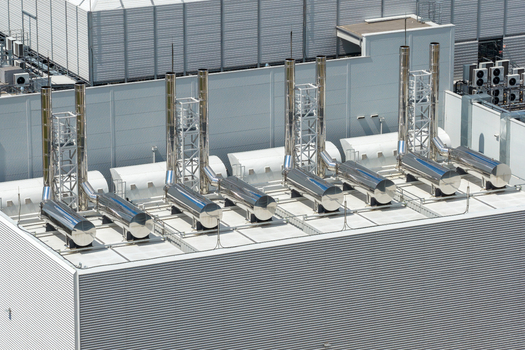 Aerial view of the industrial rooftop of an AI data center featuring rows of silver ventilation pipes and cooling units in Warsaw Masovian Voivodeship Poland. Aerial view of the industrial rooftop of an AI data center featuring rows of silver ventilation pipes and cooling units in Warsaw Masovian Voivodeship Poland.
