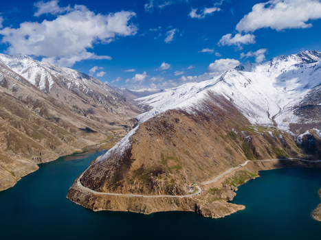 Aerial view of Lulusar Lake featuring turquoise water snow capped mountain peaks and a winding road under a blue sky with clouds in Balakot Khyber Pakhtunkhwa Pakistan. Aerial view of Lulusar Lake featuring turquoise water snow capped mountain peaks and a winding road under a blue sky with clouds in Balakot Khyber Pakhtunkhwa Pakistan.