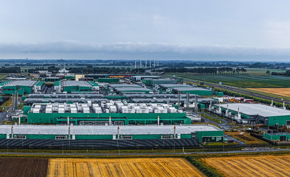 Aerial view of Agriport A7 industrial complex featuring large green roofed facilities surrounding agricultural fields and distant wind turbines in Middenmeer Noord Holland Netherlands. Aerial view of Agriport A7 industrial complex featuring large green roofed facilities surrounding agricultural fields and distant wind turbines in Middenmeer Noord Holland Netherlands.