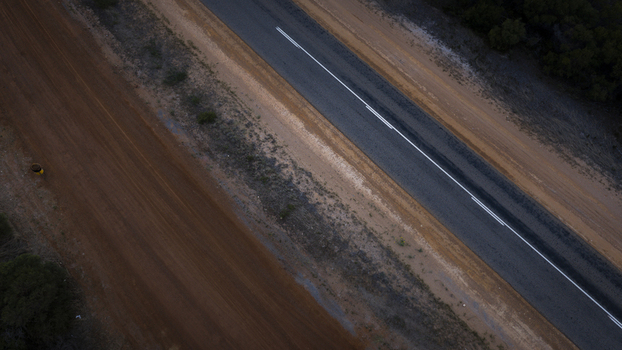Aerial view of a paved road running parallel to a dirt track through the arid landscape of Western Australia Perth Western Australia Australia.