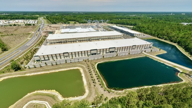 Aerial view of industrial warehouses on Foundry Lane with retention ponds and a highway surrounded by dense green forest in World Golf Village Florida United States.