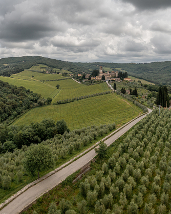 Aerial view of Passignano village nestled among lush green vineyards and olive groves under a cloudy sky in Passignano Toscana Italy. Aerial view of Passignano village nestled among lush green vineyards and olive groves under a cloudy sky in Passignano Toscana Italy.