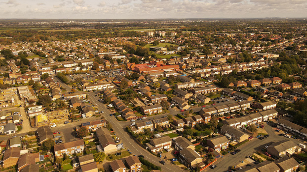Aerial view of a suburban residential neighborhood featuring rows of houses winding streets and green spaces under a cloudy sky in England United Kingdom. Aerial view of a suburban residential neighborhood featuring rows of houses winding streets and green spaces under a cloudy sky in England United Kingdom.