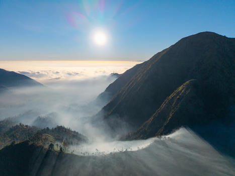 Aerial view of the mountainous landscape with mist filled valleys and dramatic sunlight illuminating the peaks in Sukapura East Java Indonesia. Aerial view of the mountainous landscape with mist filled valleys and dramatic sunlight illuminating the peaks in Sukapura East Java Indonesia.