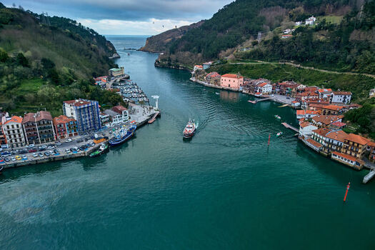 Pasai Donibane Spain 10 March 2026 Aerial view of the Harbour mouth of Pasaia with a boat navigating the waterway between colorful houses and lush green hills. Pasai Donibane Spain 10 March 2026 Aerial view of the Harbour mouth of Pasaia with a boat navigating the waterway between colorful houses and lush green hills.