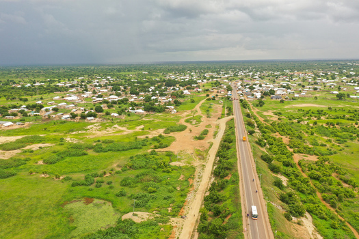Aerial view of the town of Buipe with its scattered buildings lush green vegetation and a long road stretching through the landscape in Buipe Savannah Region Ghana.