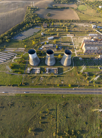 Aerial view of the abandoned Inota Power Plant cooling towers surrounded by industrial structures fields and a road in Varpalota Hungary. Aerial view of the abandoned Inota Power Plant cooling towers surrounded by industrial structures fields and a road in Varpalota Hungary.