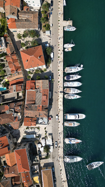 Aerial view of the historic harbor with white yachts moored along the stone quay and traditional red tiled rooftops in Vis Split Dalmatia County Croatia. Aerial view of the historic harbor with white yachts moored along the stone quay and traditional red tiled rooftops in Vis Split Dalmatia County Croatia.