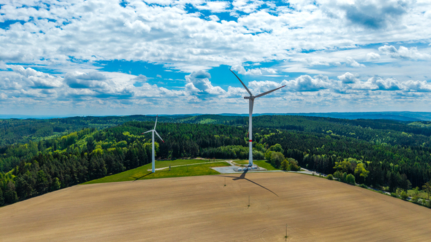 Aerial view of Zipotin wind turbines standing on a green hill overlooking dense forests and agricultural fields under a cloudy blue sky Gruna Pardubicky kraj Czechia. Aerial view of Zipotin wind turbines standing on a green hill overlooking dense forests and agricultural fields under a cloudy blue sky Gruna Pardubicky kraj Czechia.