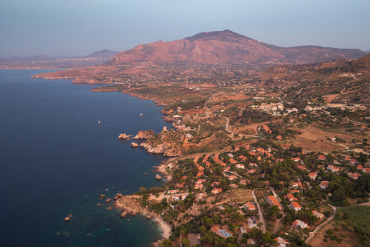 Aerial view of Riserva Naturale Orientata dello Zingaro featuring rugged coastal cliffs Mediterranean sea and scattered buildings along the coastline in San Vito Lo Capo Sicilia Italy. Aerial view of Riserva Naturale Orientata dello Zingaro featuring rugged coastal cliffs Mediterranean sea and scattered buildings along the coastline in San Vito Lo Capo Sicilia Italy.