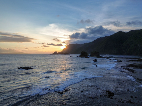 Aerial view of Papuma Beach at sunset with rocky formations crashing waves and golden light over the ocean in Jember East Java Indonesia. Aerial view of Papuma Beach at sunset with rocky formations crashing waves and golden light over the ocean in Jember East Java Indonesia.