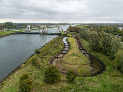 Aerial view of Sluis en stuwcomplex Hagestein with its weir and lock gates spanning the Lek river surrounded by green riverbanks a fish ladder and trees Hagestein Utrecht Netherlands.