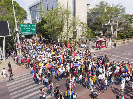 Guadalajara Mexico 01 June 2019 Aerial view of an LGBT pride parade moving through the streets with participants carrying rainbow flags and umbrellas.