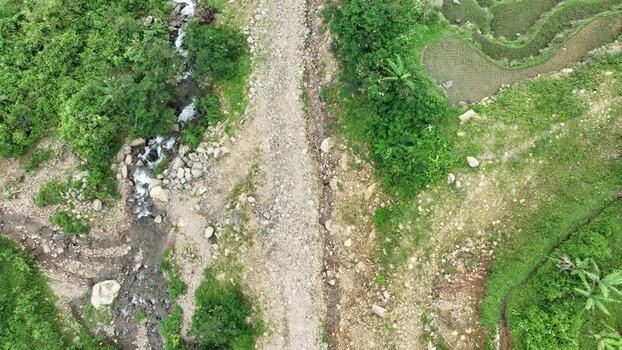 Aerial view of a rocky path and stream by terraced fields Indonesia.