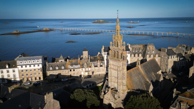 Aerial view of the historic Notre Dame de Croaz Batz church standing proudly against the tranquil sea with Île de Batz visible in the distance Roscoff Bretagne France. Aerial view of the historic Notre Dame de Croaz Batz church standing proudly against the tranquil sea with Île de Batz visible in the distance Roscoff Bretagne France.